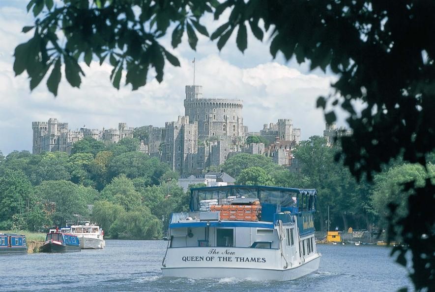 Photograph of a pleasure boat on the River Thames, with the the Tower of London in the background
